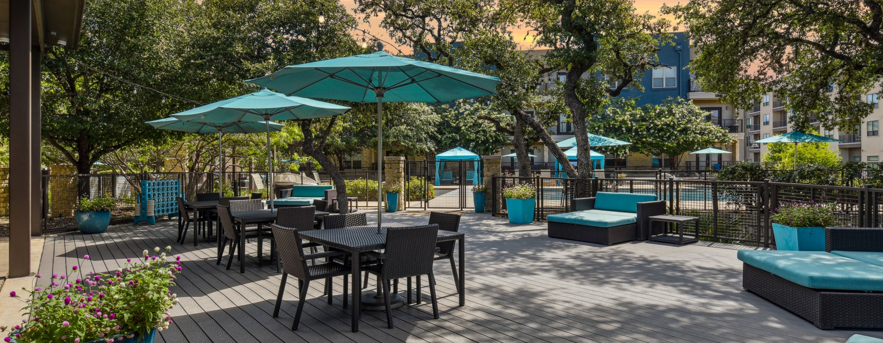 Deck beneith trees and patio furniture with umbrellas and day beds